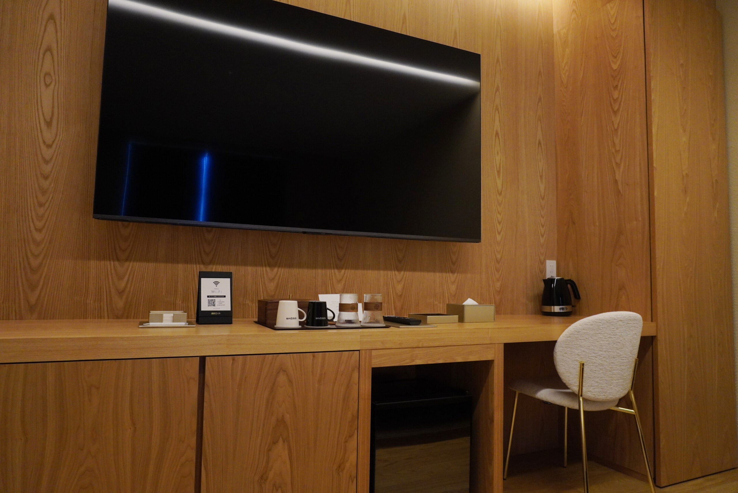 弊社で造作したテレビボードとミニバーを一体化した客室のライティングデスク
